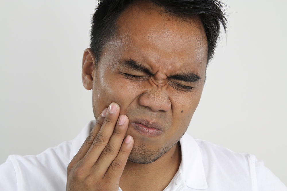 Man winces from tooth pain and looking for an emergency dentist appointment in Fayetteville, AR.