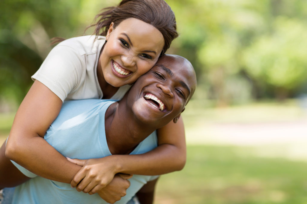 Young couple with beautiful smiles due to teeth whitening at McQueen Dental in Fayetteville, AR.